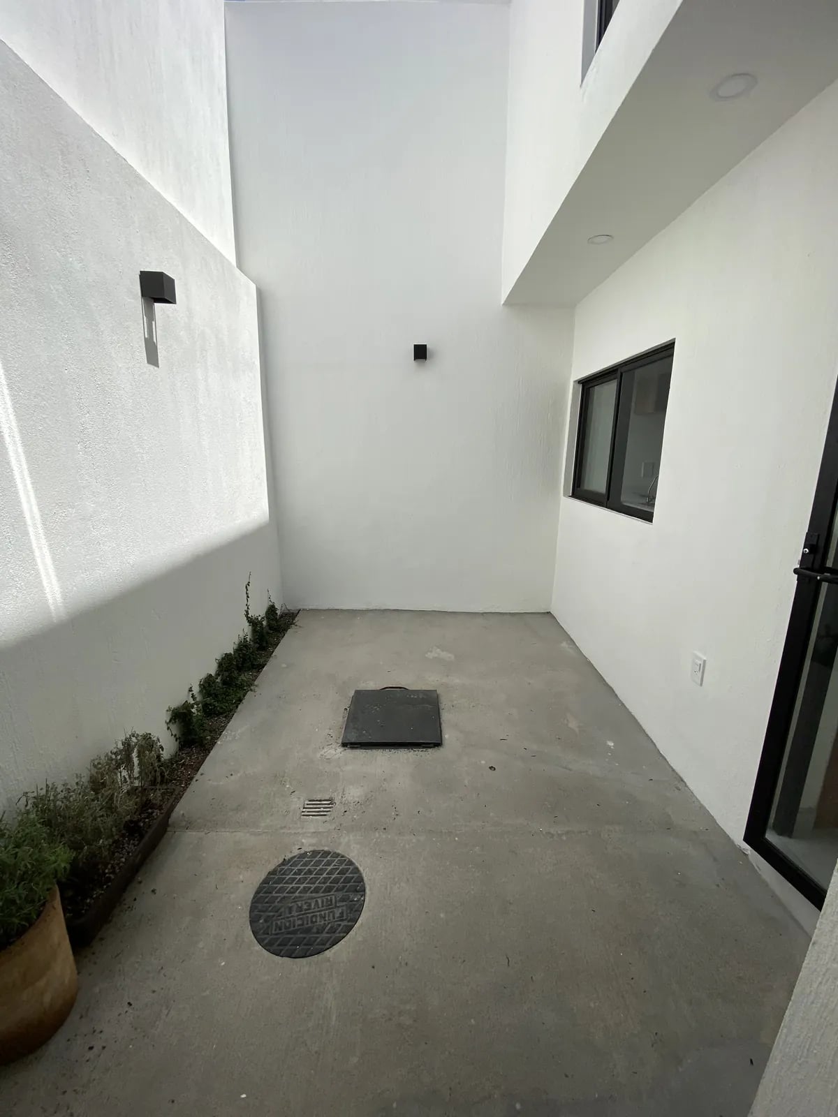 Patio interior renovado con piso de concreto y muros blancos
